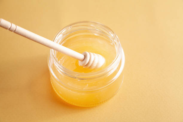 istock Honey jar with dipper on yellow background. 1323650339