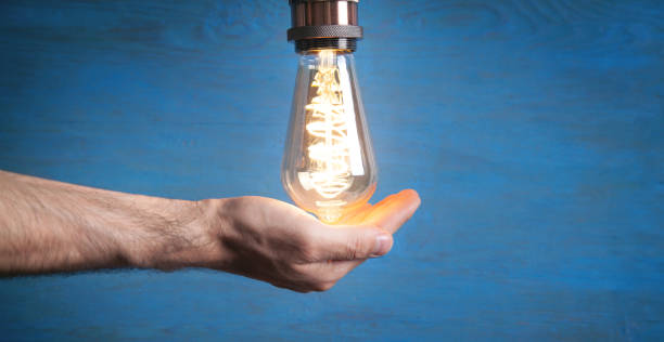 istock Male hand holding vintage modern light bulb. Inspiration and creativity 1323650351