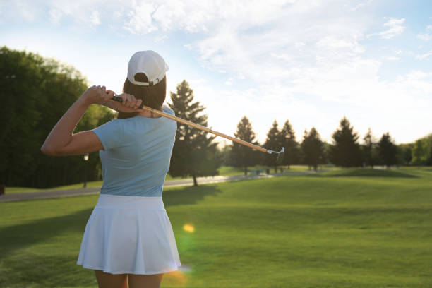 istock Woman playing golf on green course, back view 1323651336