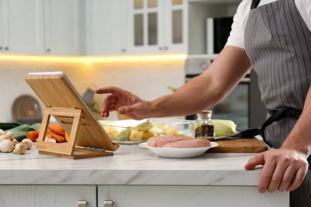 istock Man watching online cooking course via tablet in kitchen, closeup 1323651669