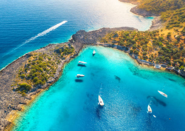 여름에 일몰에 바다에 아름다운 요트와 보트의 공중 보기. 터키의 악보룸 코유. 고급 요트, 요트, 요트, 맑은 푸른 물, 바위, 하늘, 산 및 녹색 나무의 최고 전망. 여행하다 - 터키 뉴스 사진 이미지