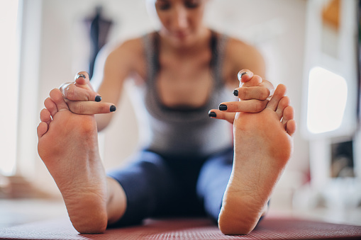 One woman, beautiful fit woman exercising yoga at home. She is holding her toes.