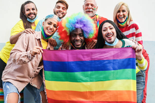 istock Gay people dance at pride parade with LGBT flags while wearing protective face mask - Main focus on left girl face 1323655228
