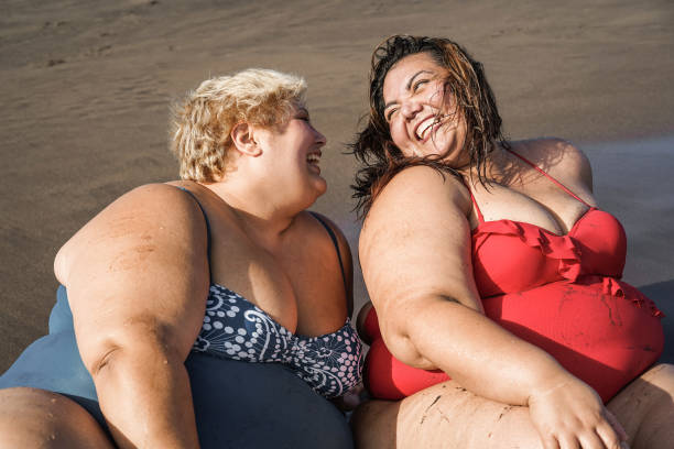 istock Plus size women sitting on the beach having fun during summer vacation - Focus on faces 1323655410