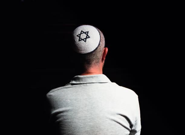 istock Young Jewish man wearing skull cap praying inside synagogue 1323656023