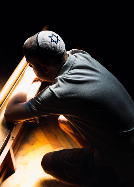 istock Young Jewish man wearing skull cap praying inside synagogue 1323656065