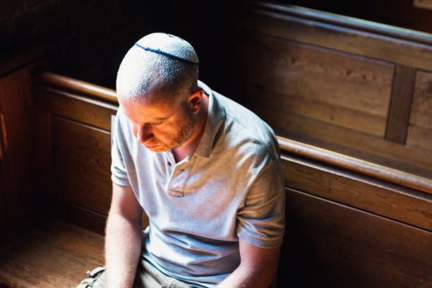 istock Young Jewish man wearing skull cap praying inside synagogue 1323656070