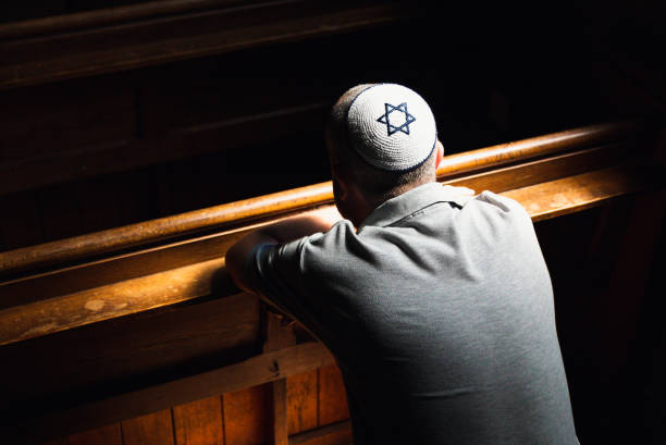 istock Young Jewish man wearing skull cap praying inside synagogue 1323656071