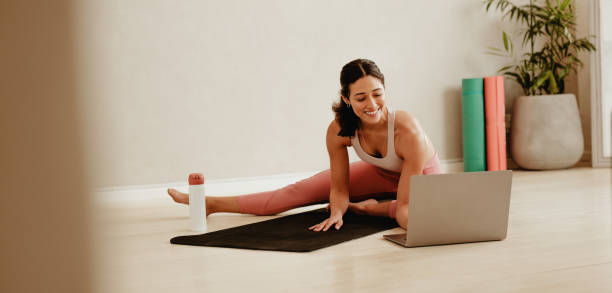 istock Woman stretching watching online training video on laptop 1323656633