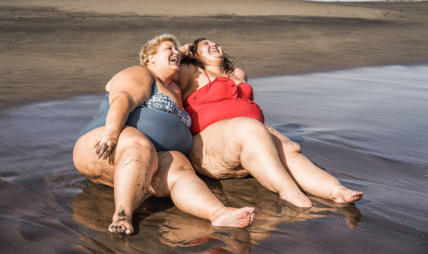 istock Plus size women sitting on the beach having fun during summer vacation - Focus on faces 1323656889