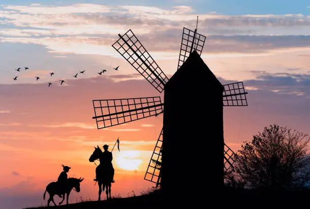 Photo of Don Quijote and Sancho Panza at the windmills in sunset