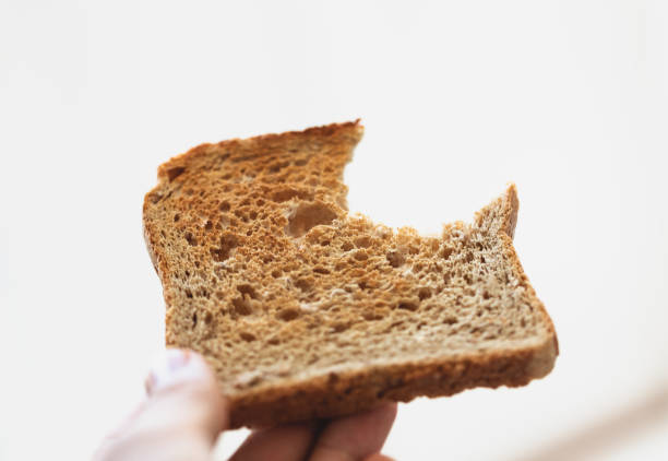 istock Holding piece of toast, making breakfast, smooth neutral background. 1323661990