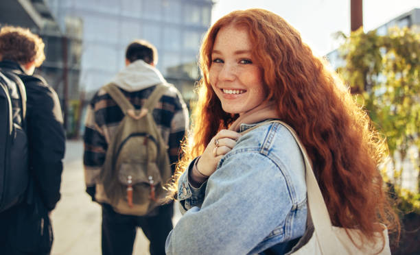 Girl going for lecture in college Girl looking back and smiling in college campus. Female student with red dyed hair going for her lecture. dyed red hair photos stock pictures, royalty-free photos & images