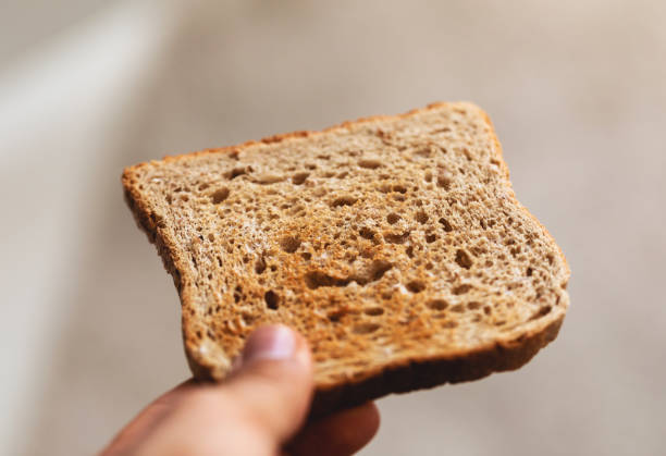 istock Holding piece of toast, making breakfast, smooth neutral background. 1323662298