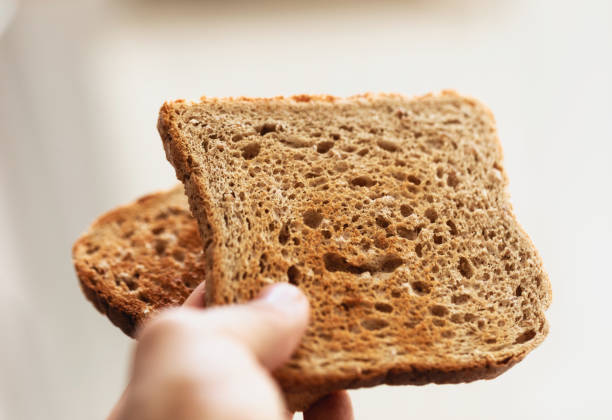 istock Holding piece of toast, making breakfast, smooth neutral background. 1323662445