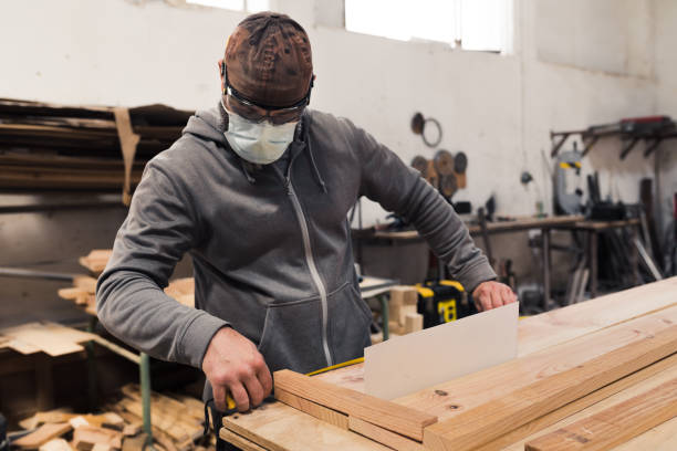 istock Carpenter with mask measuring a wood 1323665395