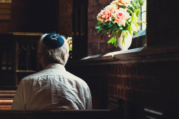 istock Senior Jewish man wearing skull cap praying inside synagogue 1323665547