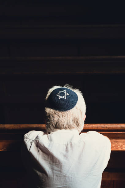 istock Senior Jewish man wearing skull cap praying inside synagogue 1323665555