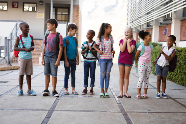istock Group of diverse students with backpacks smiling while looking at each other at school 1323667123