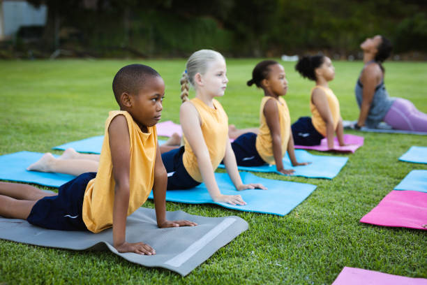 Female teacher and group of diverse students performing stretching exercise in the garden at school Female teacher and group of diverse students performing stretching exercise in the garden at school. school and education concept secondary school activities stock pictures, royalty-free photos & images