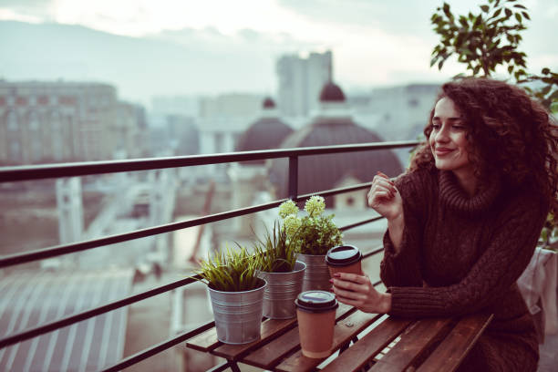 istock Cute Curly Female Enjoying Takeaway Coffee On Building Rooftop During Sunset 1323668742