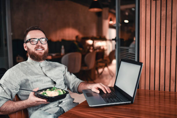 istock Bearded Male Freelancer Enjoying Salad Lunch While Working On Laptop In Restaurant 1323669456