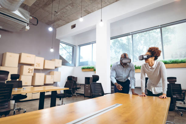 istock Two diverse businesspeople sitting at table and using vr headsets 1323669847