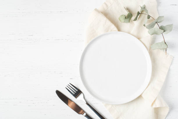 istock An empty plate and cutlery on a white table. 1323674057