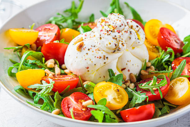 primo piatto di insalata di burrata con rucola e pomodori. - caprese salad foto e immagini stock