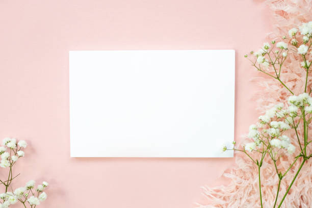 istock Blank white sheet on beige background and natural pink flower. Top view, space for text. 1323674428