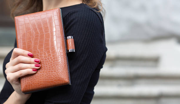 Woman holding brown leather clutch Closeup shot of a female hand holding small leather brown  clutch. Space for text clutch bag stock pictures, royalty-free photos & images