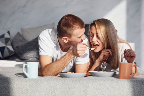 istock Young lovely couple have a breakfast at home while lying down on bed 1323678864