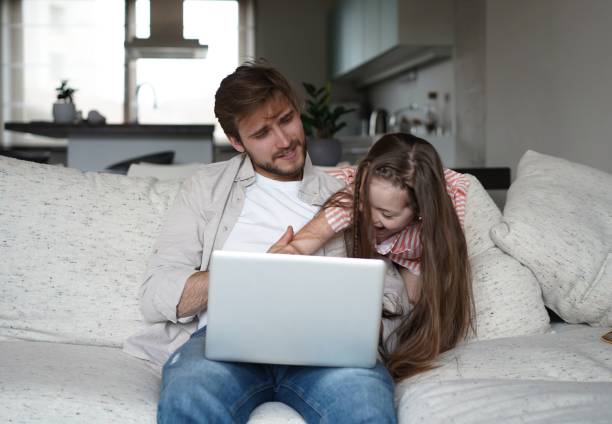 istock Daughter disturbing stressed father in living room. Working from home during quarantine. 1323679038