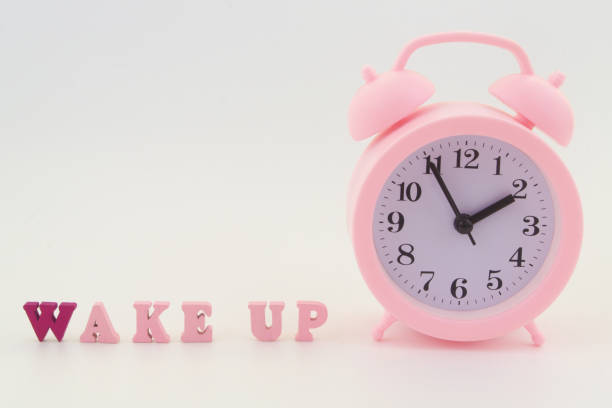 istock Pink alarm clock and letters wake up 1323683863