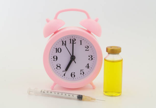 istock Vaccine bottle and syringe with alarm clock on gray background. 1323683872
