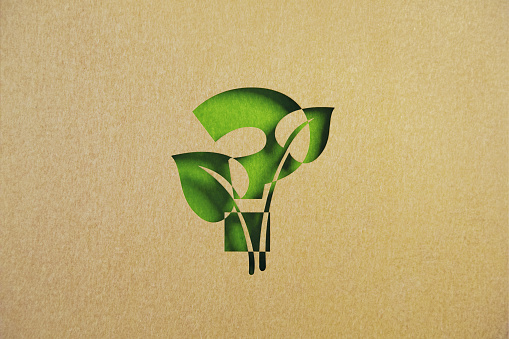 Cut out leaf shaped made of recycled paper intersect with question mark on green background. Horizontal composition with copy space. Q and A concept.