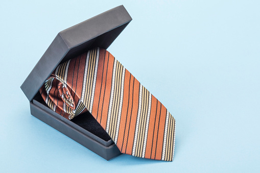 Silk tie in a gift box on blue with copy space for fathers day