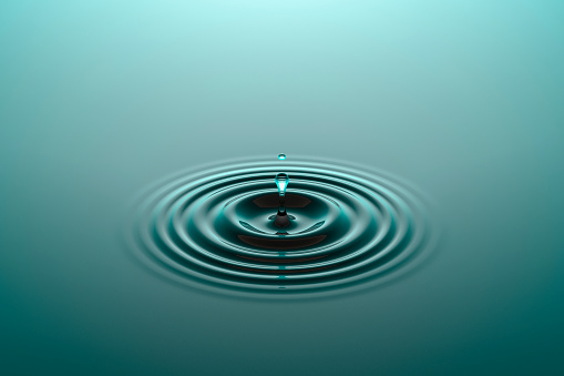 Water drop falling into water surface with ripples