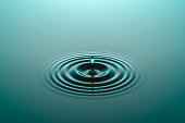 Water drop falling into water surface with ripples