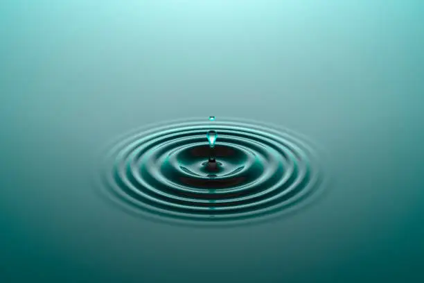 Photo of Water drop falling into water surface with ripples