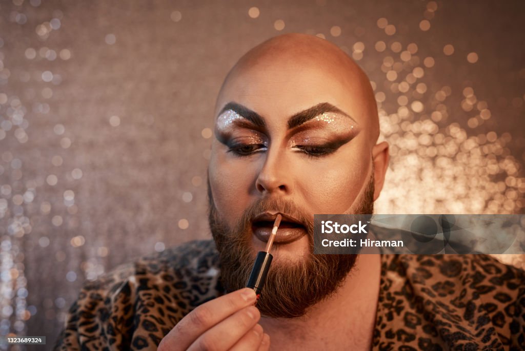 Shot of a young man applying theatrical makeup to his face in a studio Getting cute Human Lips Stock Photo