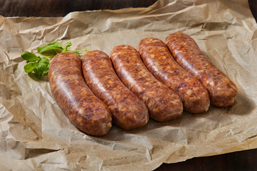 Delicious fresh small vegetarian sausages with salt, spices and herbs on a dark concrete background