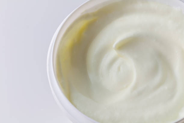 istock White yogurt in large plastic container close up isolated on white with space for text - Greek yoghurt background 1323689989