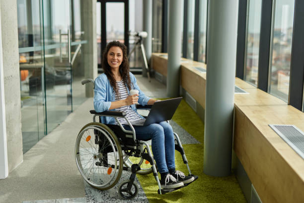 istock Disabled female IT worker in wheelchair working with laptop 1323690101