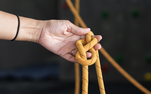 Focus and close up to hand holding a yellow rope for rock climbing