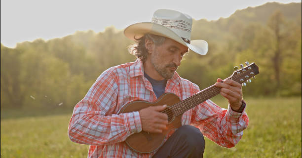 istock Cowboy in nature playing the guitar at sunset. Springtime staycation. 1323691704