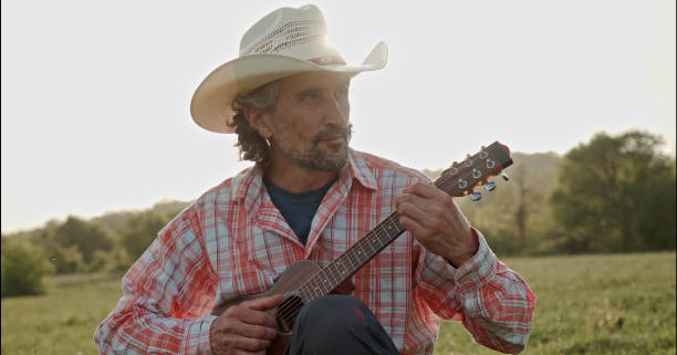 istock Cowboy in nature playing the guitar at sunset. Springtime staycation. 1323691708