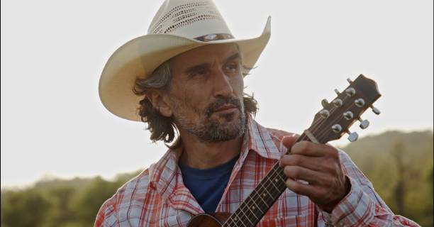 istock Cowboy in nature playing the guitar at sunset. Springtime staycation. 1323691710