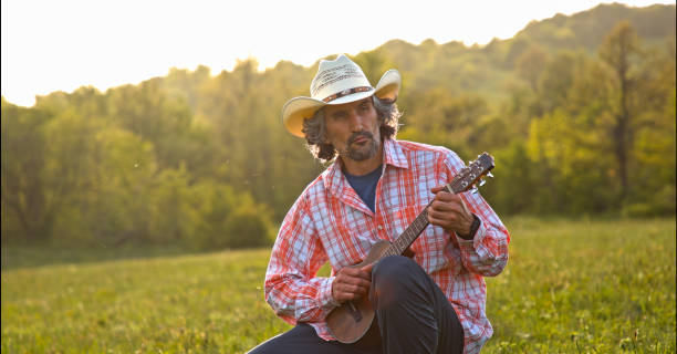 istock Cowboy in nature playing the guitar at sunset. Springtime staycation. 1323691711