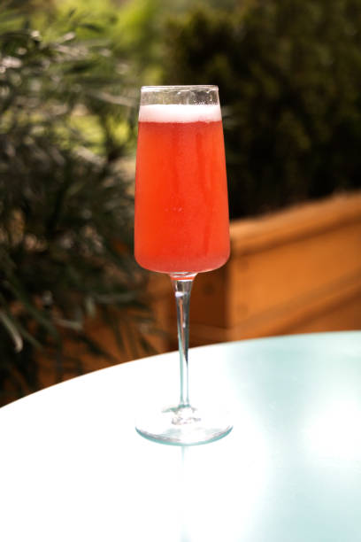 eine erdbeer-mimose, die draußen auf einem restauranttisch zum brunch mit grünen sträuchern sitzt - champagne pink strawberry champaigne stock-fotos und bilder
